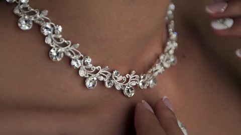 Young woman puts on a beautiful necklace