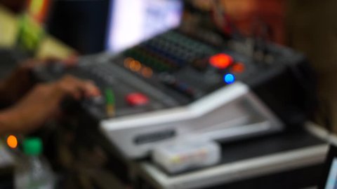 Blurred footage: Sound director working on audio mixer in professional studio. The lights blinking according the rhythm.