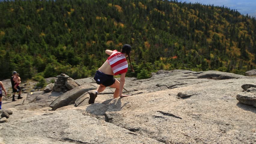 Woman hiking a trail in the Adirondack Mountains.  View looking down a mountain path as the woman descends, picking her way through the rocks. 