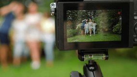 record family video on your camcorder. Happy family dancing together on the grass in a park with beautiful nature. 4k. copy space. life style. Slow motion