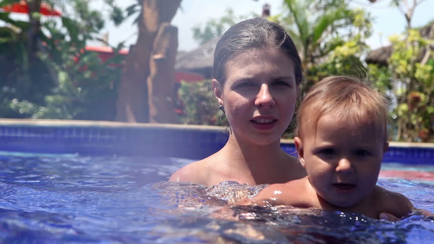 Happy pretty woman holding her daughter in swimming pool
