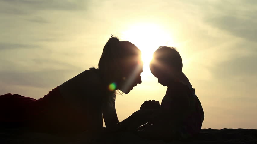 Silhouette of mother and daughter over sunset