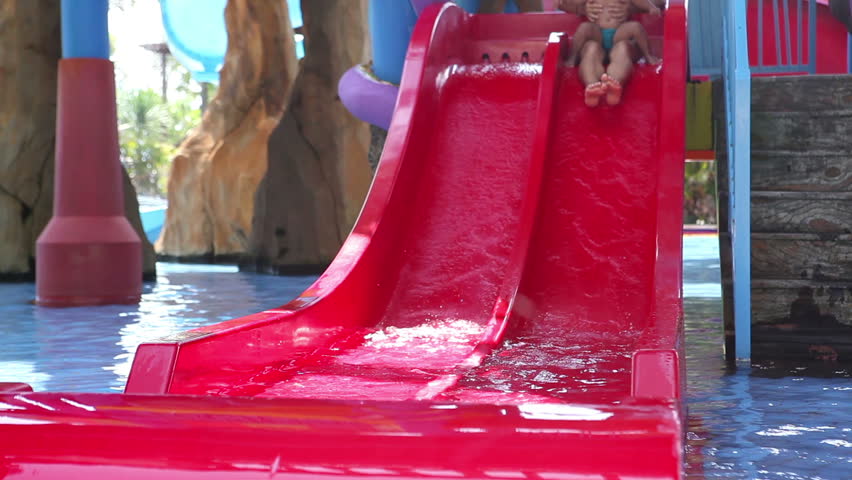 Mother with her daughter having fun on slide in aqua park