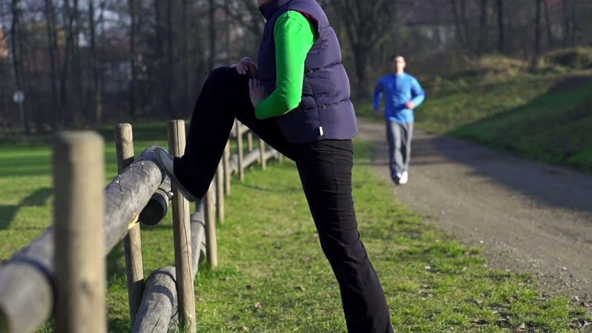 Woman stretching, man jogging in park, slow motion, shot at 240fps

