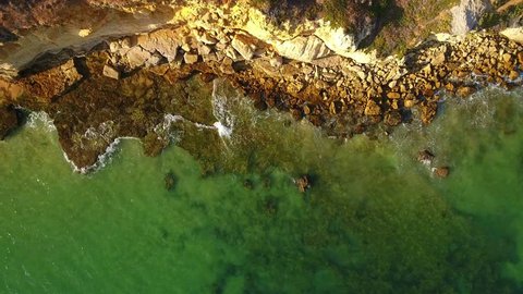 Aerial. Waves wash stones on the shore of Albufeira. Olhos de Agua