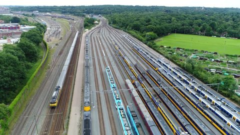 Aerial of railroad hub or railway terminal flying backwards showing trains passing by fast also showing different trains parked next to each other on the rail tracks 4k high resolution footage
