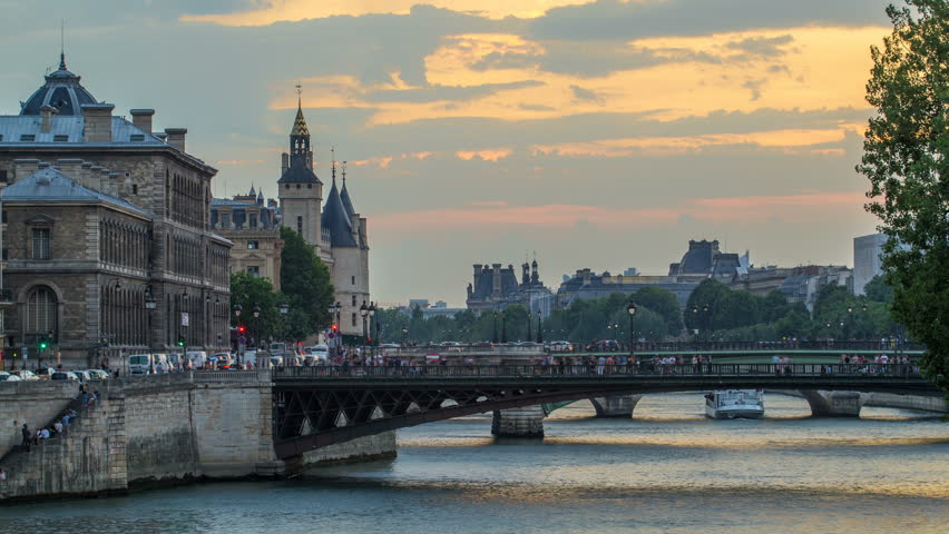 People and boats day to night transition timelapse, Le Pont D'Arcole bridge after sunset, Paris, France, Europe. Colorful sky at summer day with reflection on river Seine