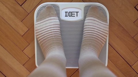 Person checking the weight on the scale. Display blinking DIET.