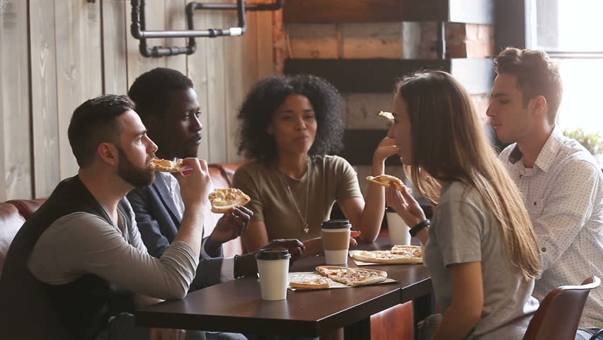 Diverse happy friends eating italian pizza together, five african and caucasian young hungry students enjoying fast food meal sharing lunch during meeting sitting at cozy pizzeria restaurant table  | Shutterstock HD Video #31517566
