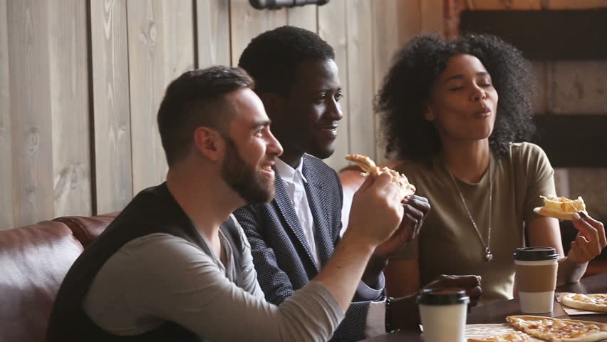 Multiracial happy young people eating pizza in pizzeria, black and white cheerful students enjoying meal dining sitting together at restaurant table, diverse hungry friends sharing lunch at meeting Royalty-Free Stock Footage #31517623