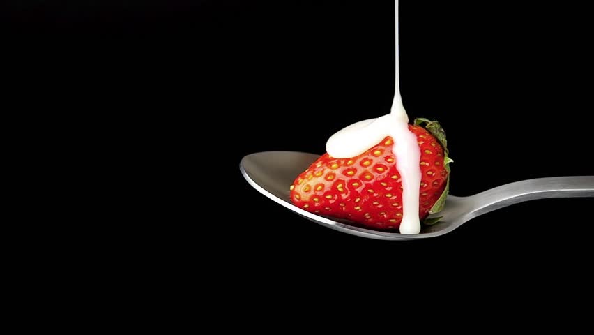 Pouring Condensed Milk on Strawberry, isolated on black