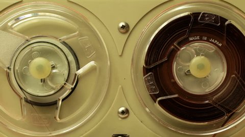 stop-motion of a small vintage reel to reel tape recorder playing from one side to the other