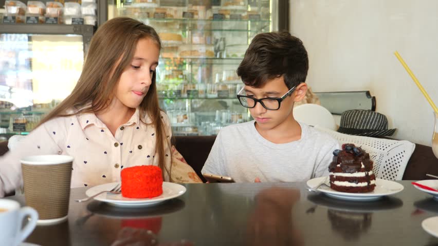 children, brother and sister, twins eat a delicious dessert in a cafe. 4k slow motion