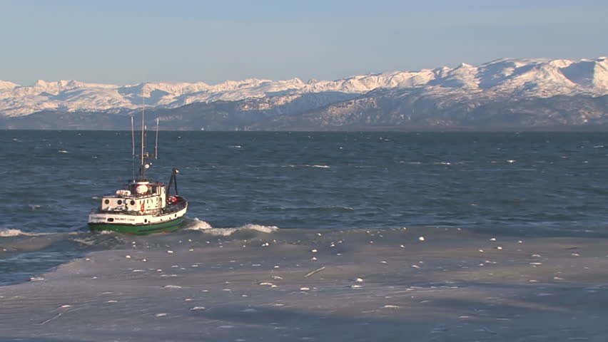 HOMER, AK - CIRCA 2012: A green utility/fishing boat of classic design heads out