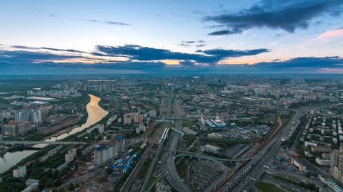 Aerial top view of Moscow city day to night transition timelapse after sunset. Form from the observation platform of the business center of Moscow City. Moscow river and traffic on roads at summer day