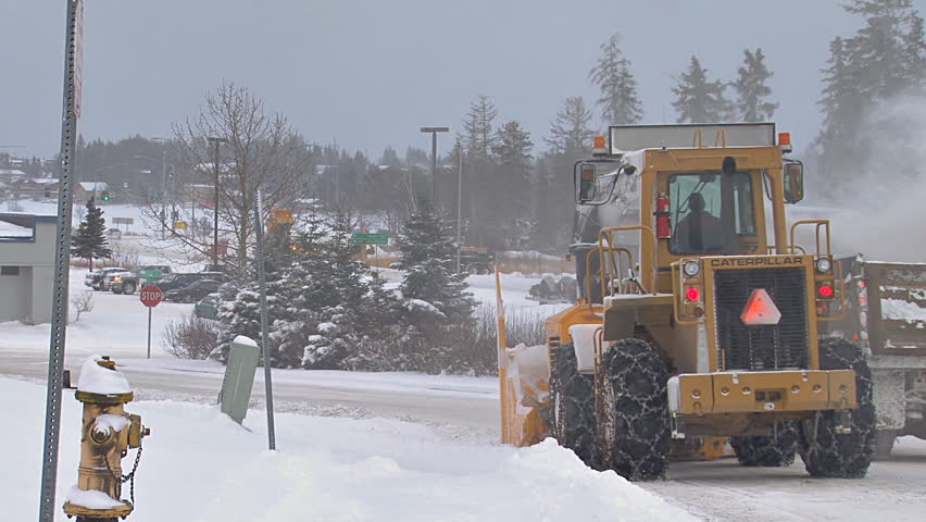 HOMER, AK - CIRCA 2011: Snow blower on an excavator paired with a dump truck to