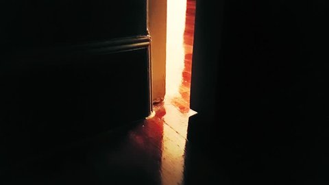 close-up of Door opening in the dark at house with light shining