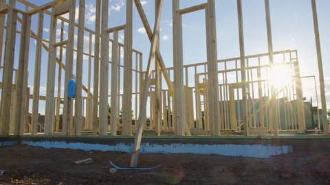 Move Left and Enter Residential Framed Home. view moves left as sun flare wraps around the beams of the new residential home framing wood walls
