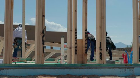 Construction Workers Lift Framed Wall Into Place. view moves right as construction workers lift a framed wall into place for residential home construction
