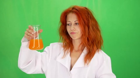 Young beautiful scientist girl taste orange liquid from flasks at experiment green-screen