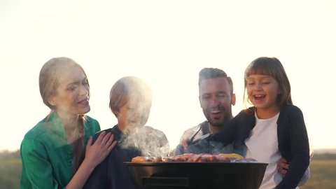 Happy family cook meat on grill.