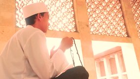 Video footage of a religious muslim person doing dhikr in the mosque while holding a praying beads