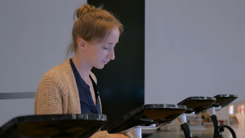 Woman using interactive touchscreen display and listening audio guide at modern history museum - scrolling and touching. Education and technology concept