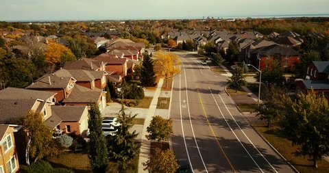 Aerial drone flight over a suburban neighbourhood in Oakville, Ontario.  Drone follows the road about 100 feet above the ground.