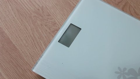 Obese woman getting on scales for weight control during healthy diet.