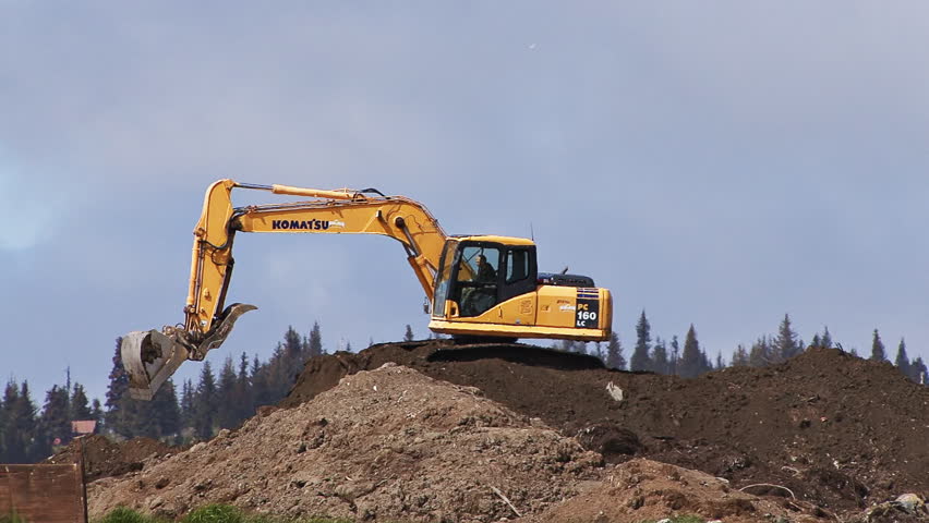 HOMER, AK - CIRCA 2012: Excavator working on mound of dirt, expanding land fill