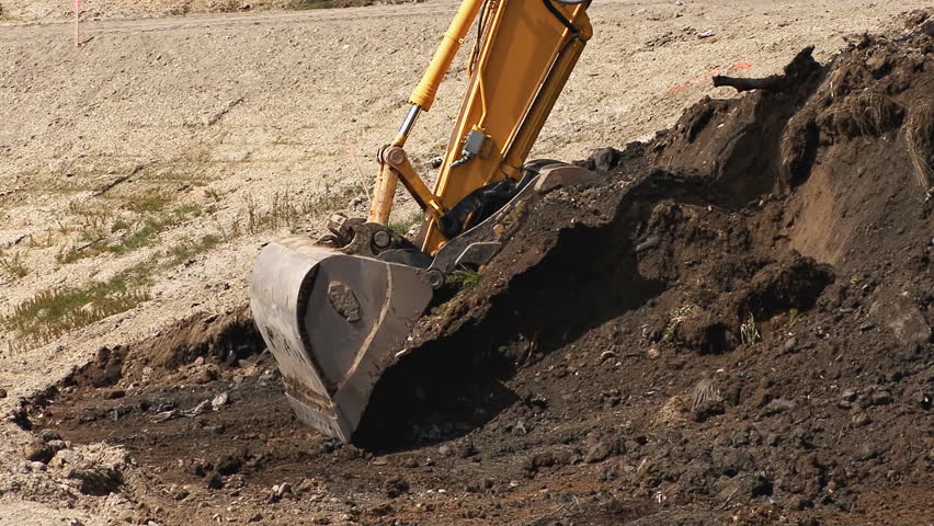 HOMER, AK - CIRCA 2012: Excavator bucket being used to scoop dirt, then tracking