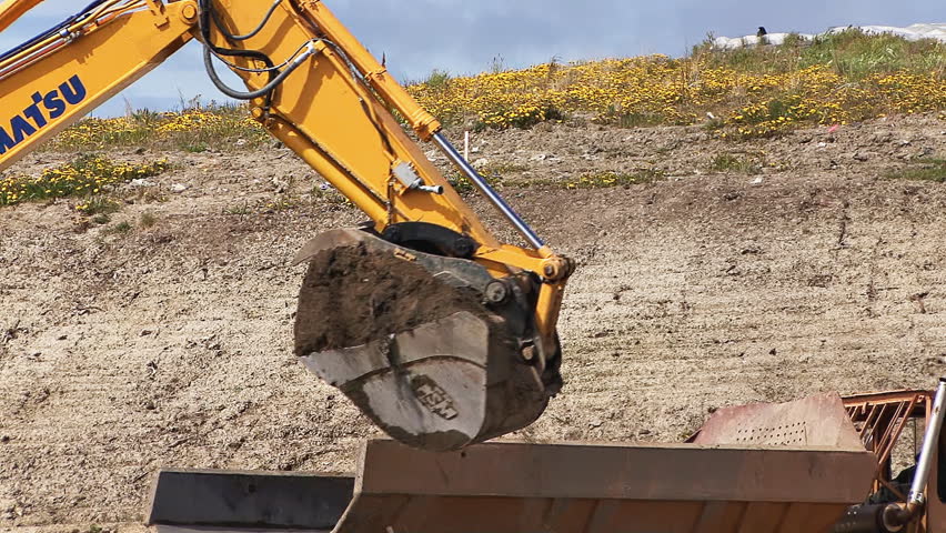 HOMER, AK - CIRCA 2012: Excavator bucket being dumped into dump truck.