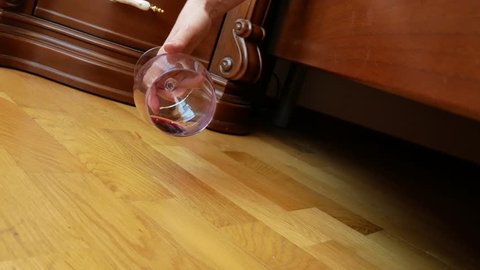 close-up, female hand dropping a glass of red wine from the bed. the remnants of wine are poured onto the floor. slow motion 4k