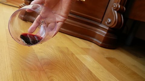 close-up, female hand dropping a glass of red wine from the bed. the remnants of wine are poured onto the floor. slow motion 4k