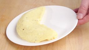 A hand holding an omelette on a plate
