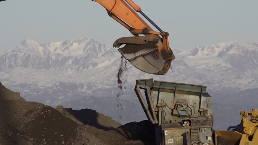 HOMER, AK - CIRCA 2012: Excavator's bucket carefully dropping gravel and dirt