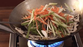 sautéing chicken and vegetables in a wok
