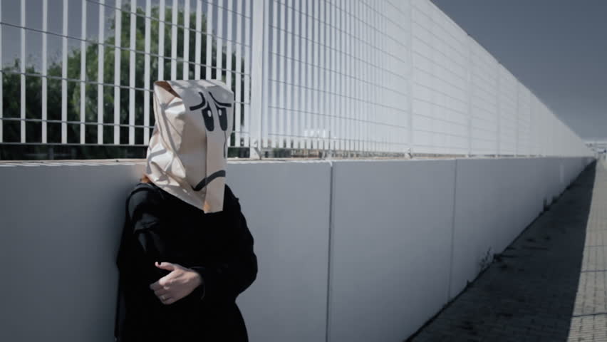 A sad grieving breadbag face at a train station in a gloomy day. Handheld shot.
