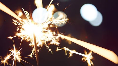 Firework sparkler burning with lights in background