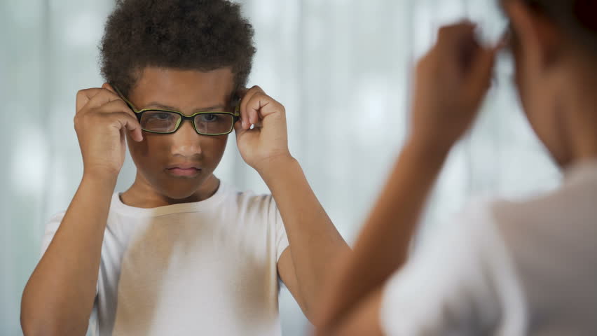 Upset Afro-American kid putting glasses on and off, eyesight problem, healthcare | Shutterstock HD Video #31577251