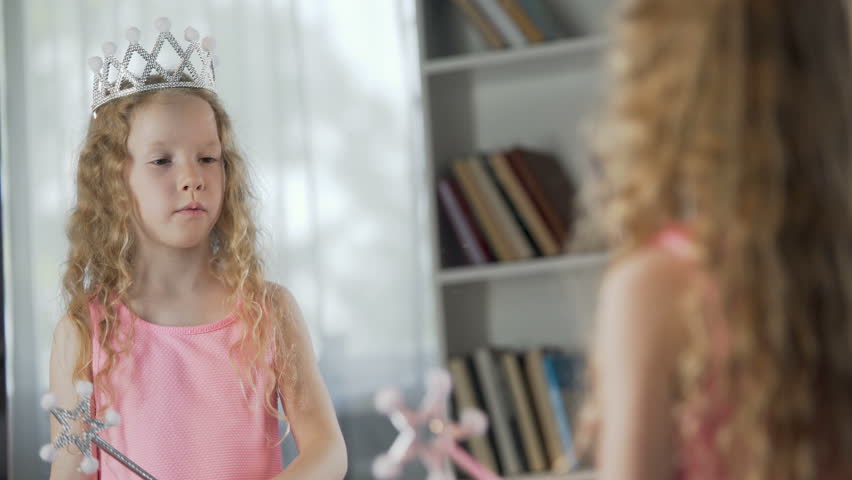 Red-haired girl playing role of magic fairy in front of mirror, future actress