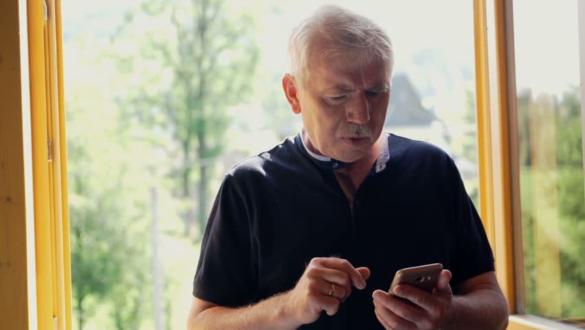 Senior man has problems with his vision while trying to read something on his mobile phone.
 Royalty-Free Stock Footage #31578745