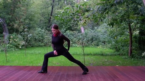 Woman doing Qigong in the park - Warrior pose