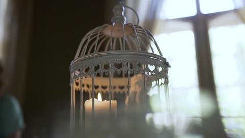 A candle in a lantern and a small decorative angel. Close up, of a burning candle in a flashlight slow motion