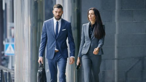 Male and Female Business People Walk and Financial Matters. They're Work in the Central Business District. Shot on RED EPIC-W 8K Helium Cinema Camera.