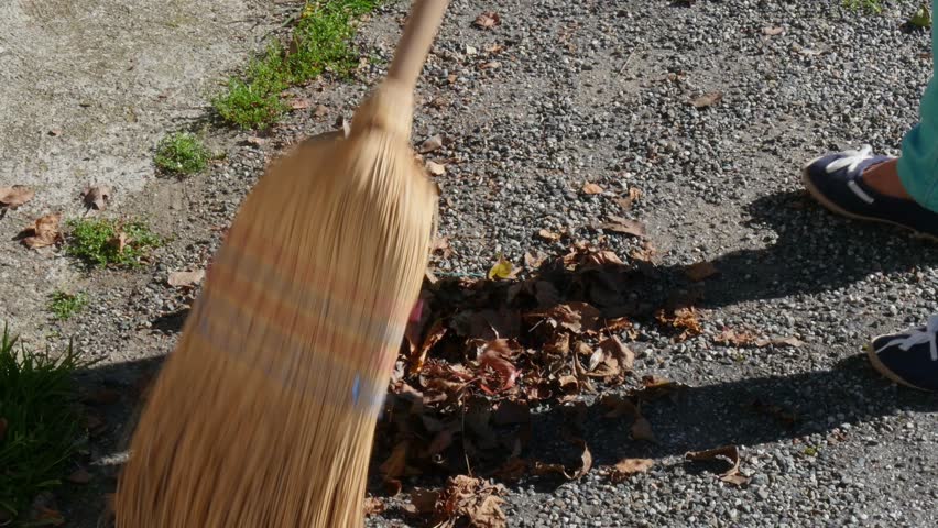 a woman sweeping the dead leaves in the garden