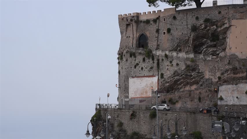 The cars drive along the mountain road that surrounds the stone cliff/ Road in the mountains 