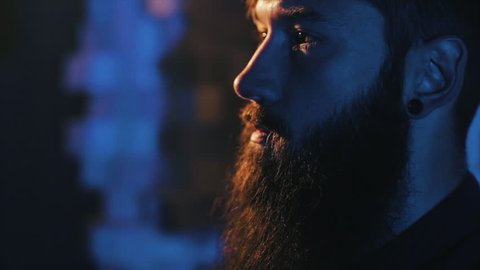 A bearded man smokes an electronic cigarette,vape,e-cigarette slow-motion,dark background