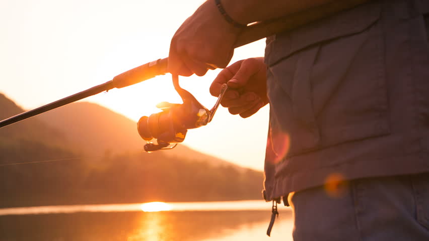 Fisherman catches a fish. Hands of a fisherman with a spinning rod in hand closeup. Spin fishing reel
