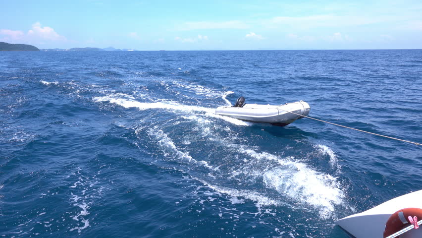 Boat is dragging dinghy on the sea.
